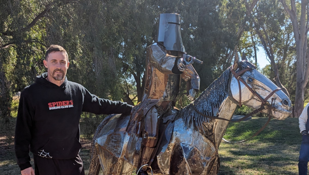 Photo of artist Luke Sheehan next to his chainsaw art sculpture